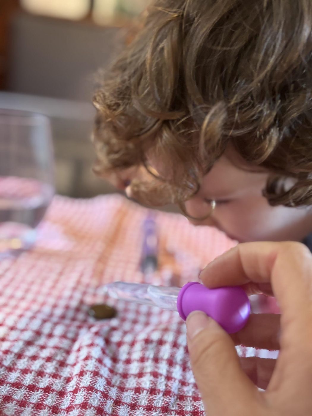 A child leaning in close to watch a coloured drop fall from a pipette